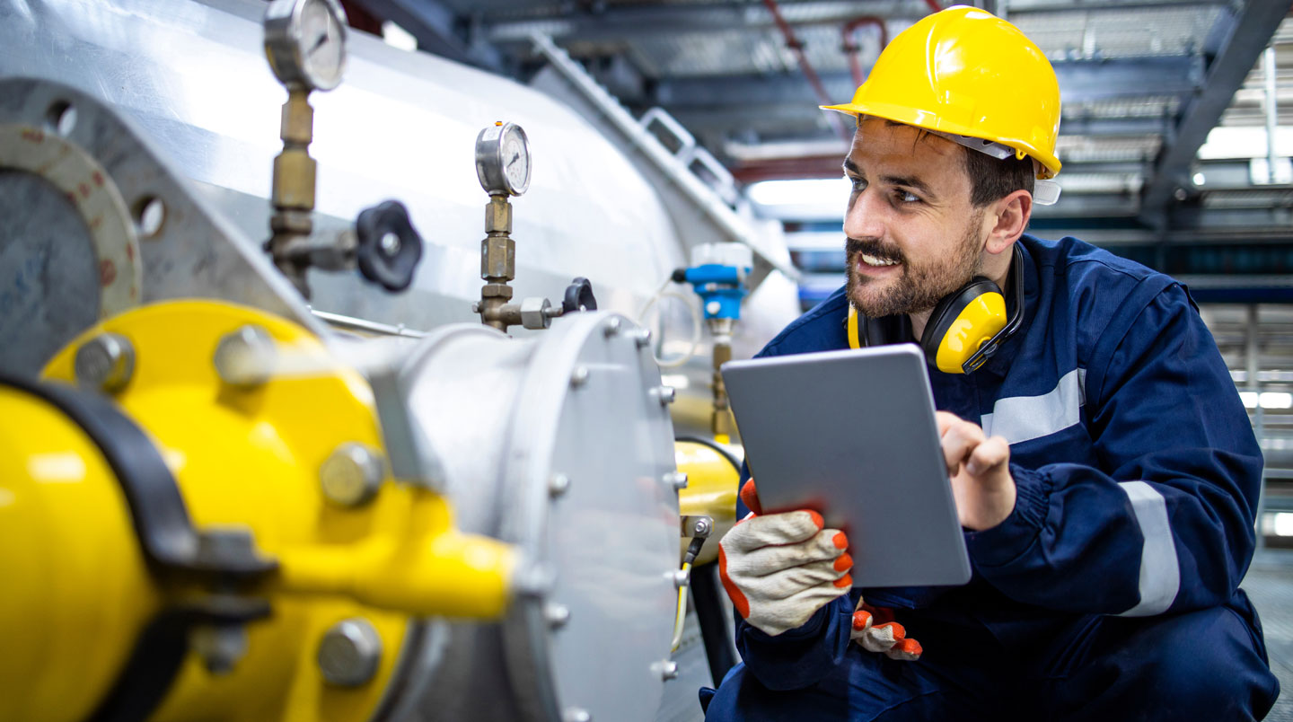 Responsable technique en usine examinant des données de consommation énergétique sur un écran de contrôle industriel